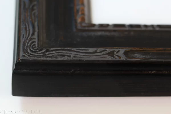 Detail of the corner of a Nouveau black with gold wood frame